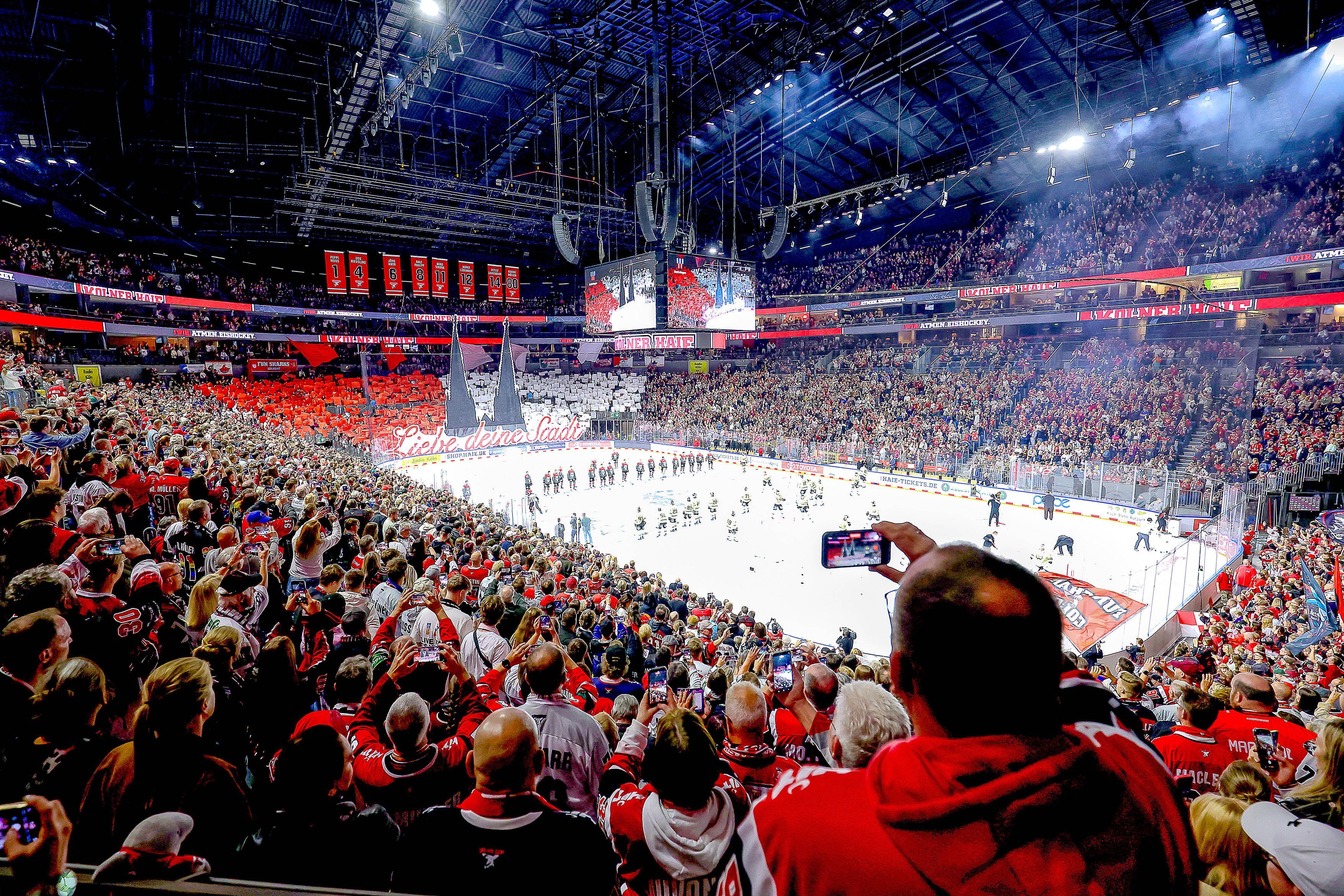 Ein Weitwinkel-Bild aus der vollen Lanxess-Arena, während die Haie-Fans auf der Südtribüne eine rot-weiße Dom-Choreografie zeigen.
