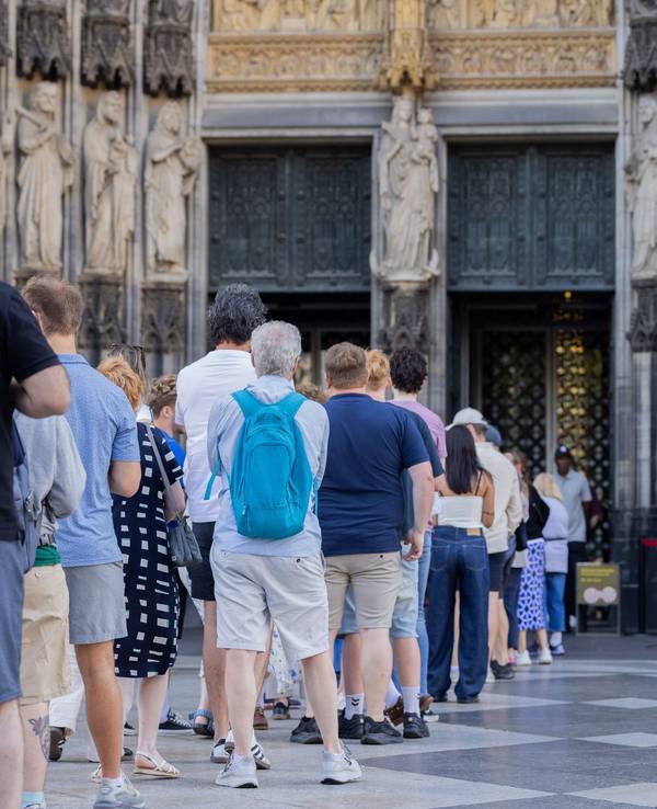 Touristen stehen vor dem Haupteingang des Kölner Doms Schlange.