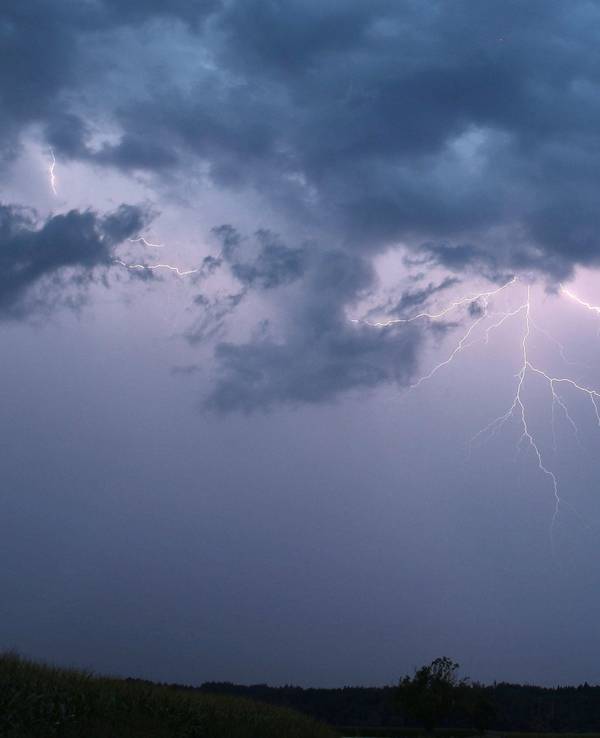 Ein Blitz zuckt bei einem Sommergewitter am abendlichen Himmel.