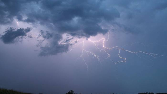 Ein Blitz zuckt bei einem Sommergewitter am abendlichen Himmel.
