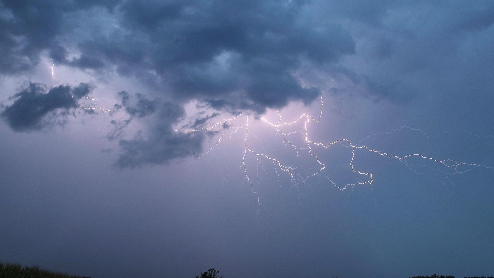 Ein Blitz zuckt bei einem Sommergewitter am abendlichen Himmel.