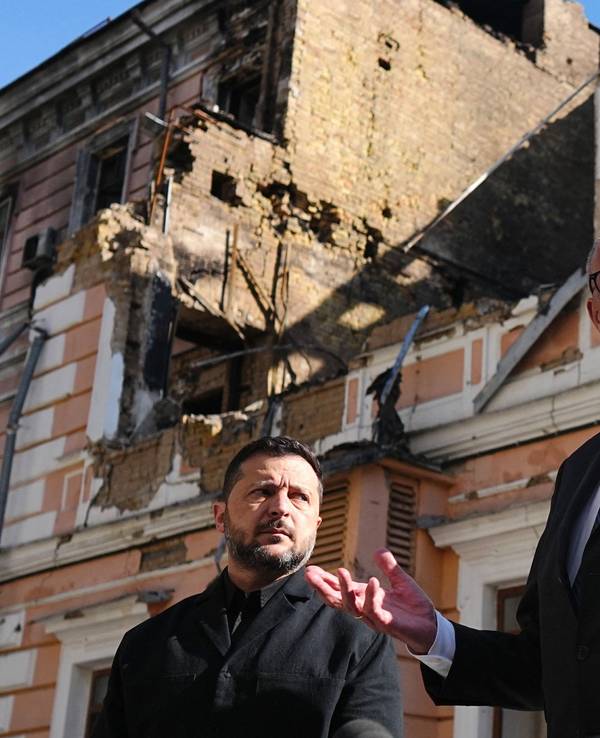 Bundeskanzler Friedrich Merz (r., CDU) und Wolodymyr Selenskyj (l.), Präsident der Ukraine, stehen am zerstörten Gebäude der Nationalen Akademie der Wissenschaften.
