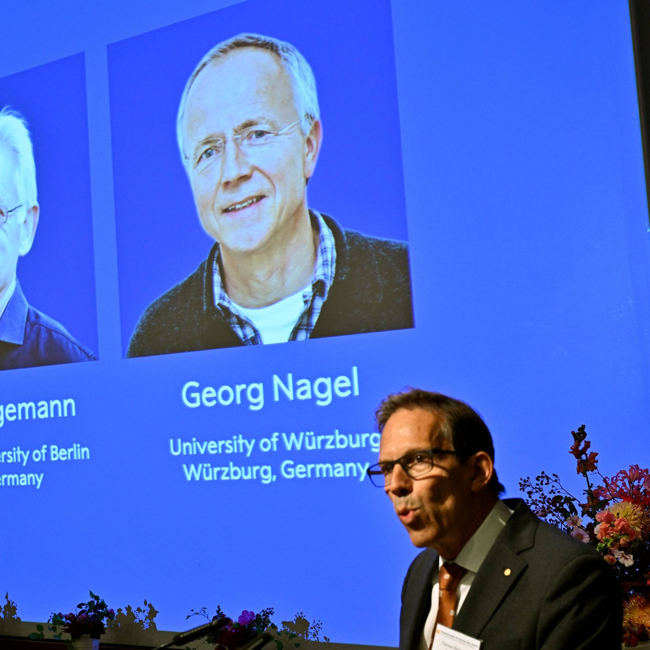 Karl Deisseroth, Peter Hegemann und Georg Nagel sind auf dem Bildschirm zu sehen, als ihnen der Nobelpreis für Physiologie oder Medizin 2026 verliehen wird.