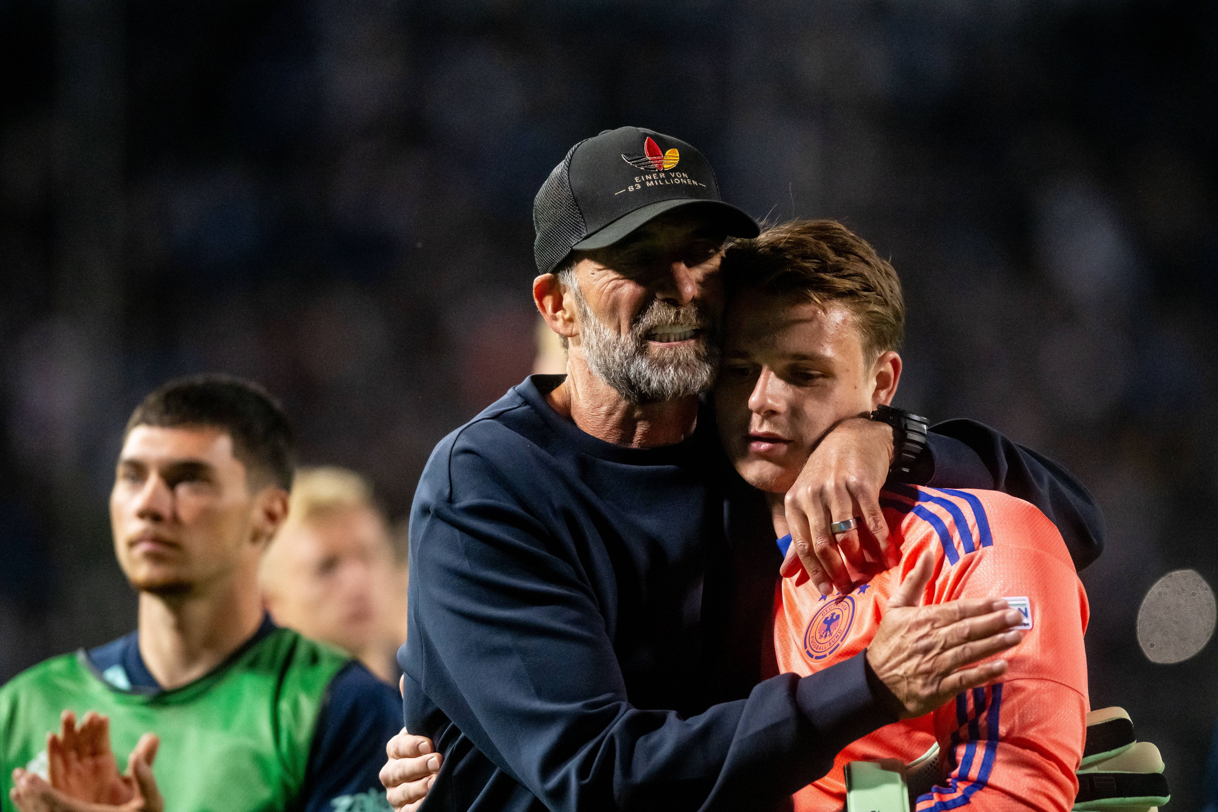 Jonas Urbig wird von seinem Trainer Jürgen Klopp umarmt.