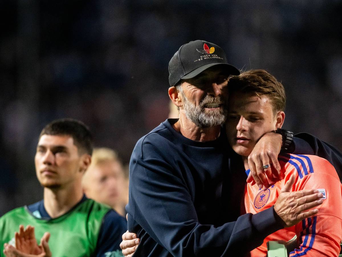 Jonas Urbig wird von seinem Trainer Jürgen Klopp umarmt.