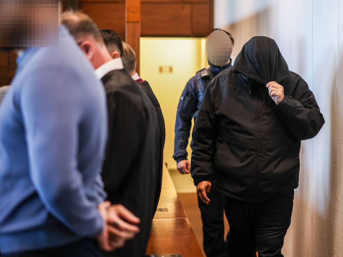 Einer der sieben Angeklagten (r.) wird von einem Justizbeamten in den Gerichtssaal gebracht.
