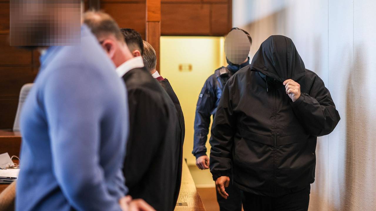 Einer der sieben Angeklagten (r.) wird von einem Justizbeamten in den Gerichtssaal gebracht.