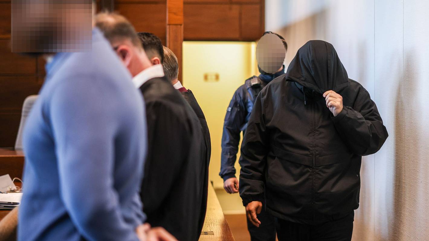 Einer der sieben Angeklagten (r.) wird von einem Justizbeamten in den Gerichtssaal gebracht.