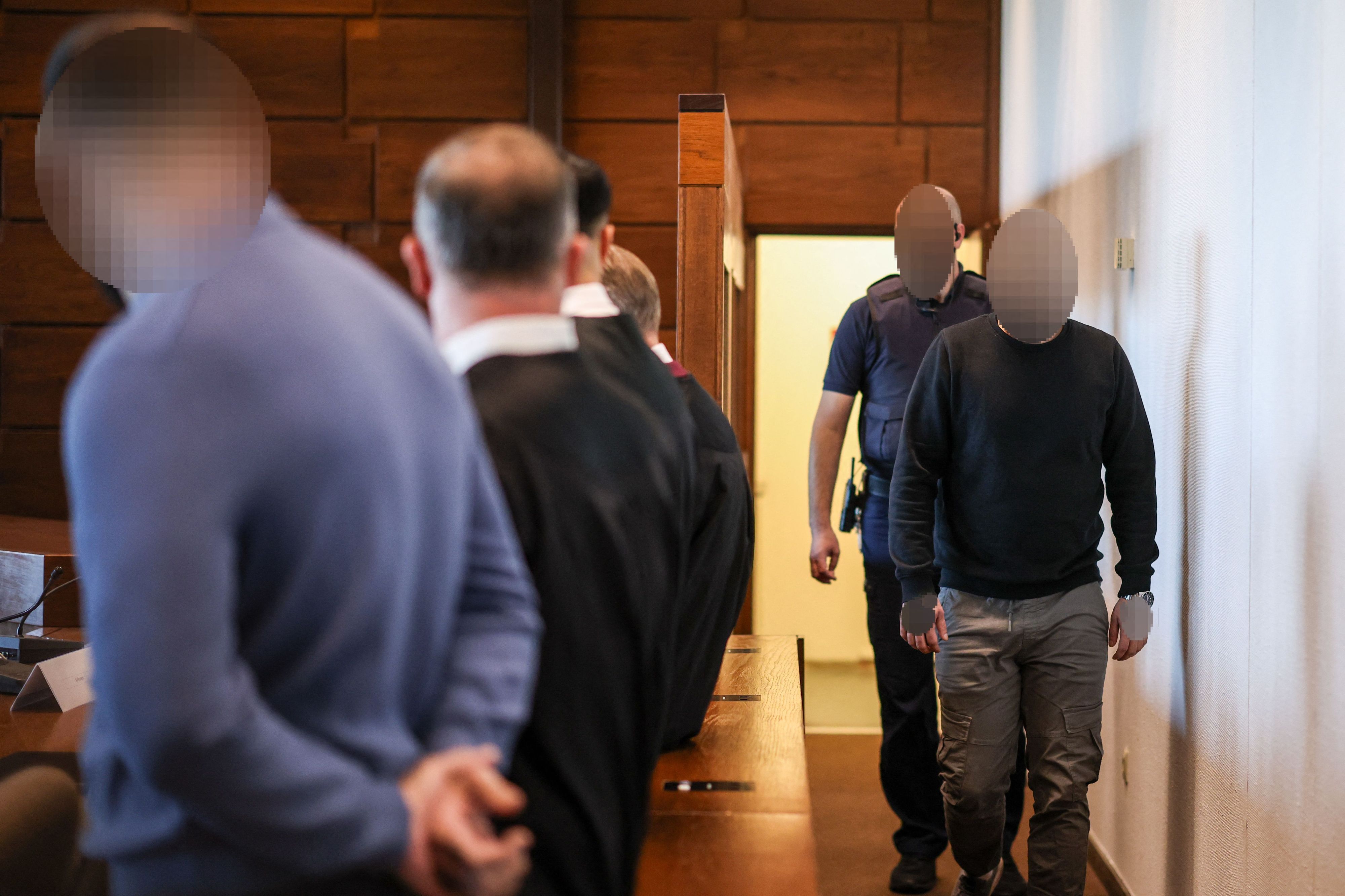 Ein Angeklagter (r) wird von einem Justizbeamten in den Gerichtssaal gebracht. Der Raubüberfall in einer Hürther Lagerhalle gilt als Auslöser einer massiven Gewaltspirale, die als „Kölner Drogenkrieg“ bekannt wurde und im Sommer 2024 Köln und die Region in Atem hielt.