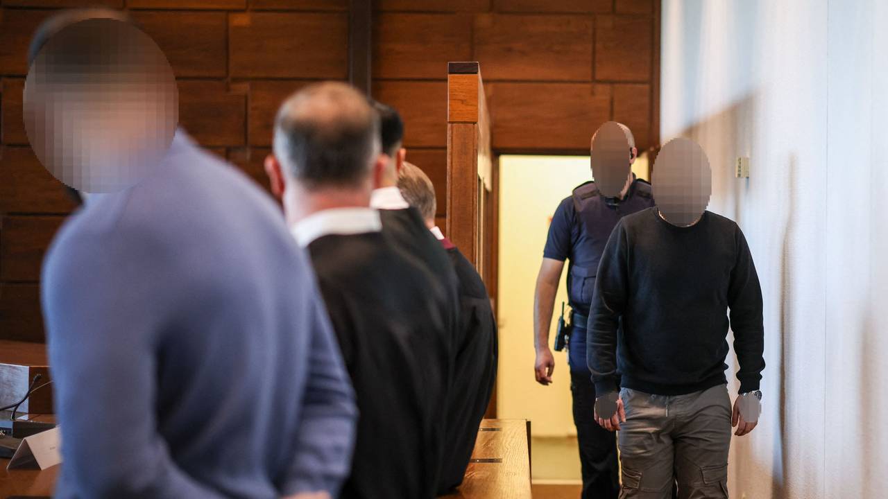 Ein Angeklagter (r) wird von einem Justizbeamten in den Gerichtssaal gebracht. Der Raubüberfall in einer Hürther Lagerhalle gilt als Auslöser einer massiven Gewaltspirale, die als „Kölner Drogenkrieg“ bekannt wurde und im Sommer 2024 Köln und die Region in Atem hielt.
