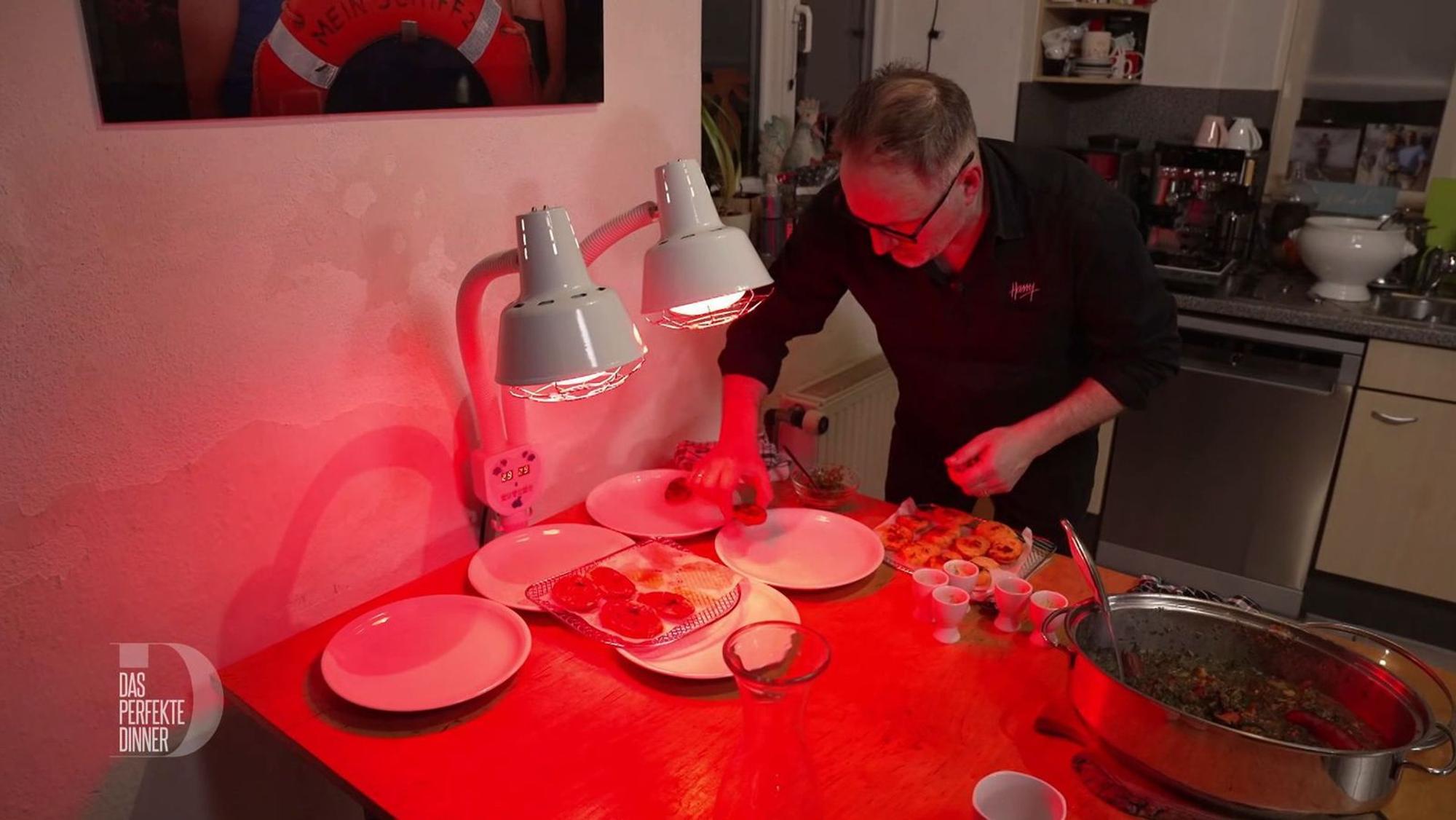 Beim wärmenden Rotlicht der Rheumalampe richtet Harry die Teller an.
(Bild: RTL)