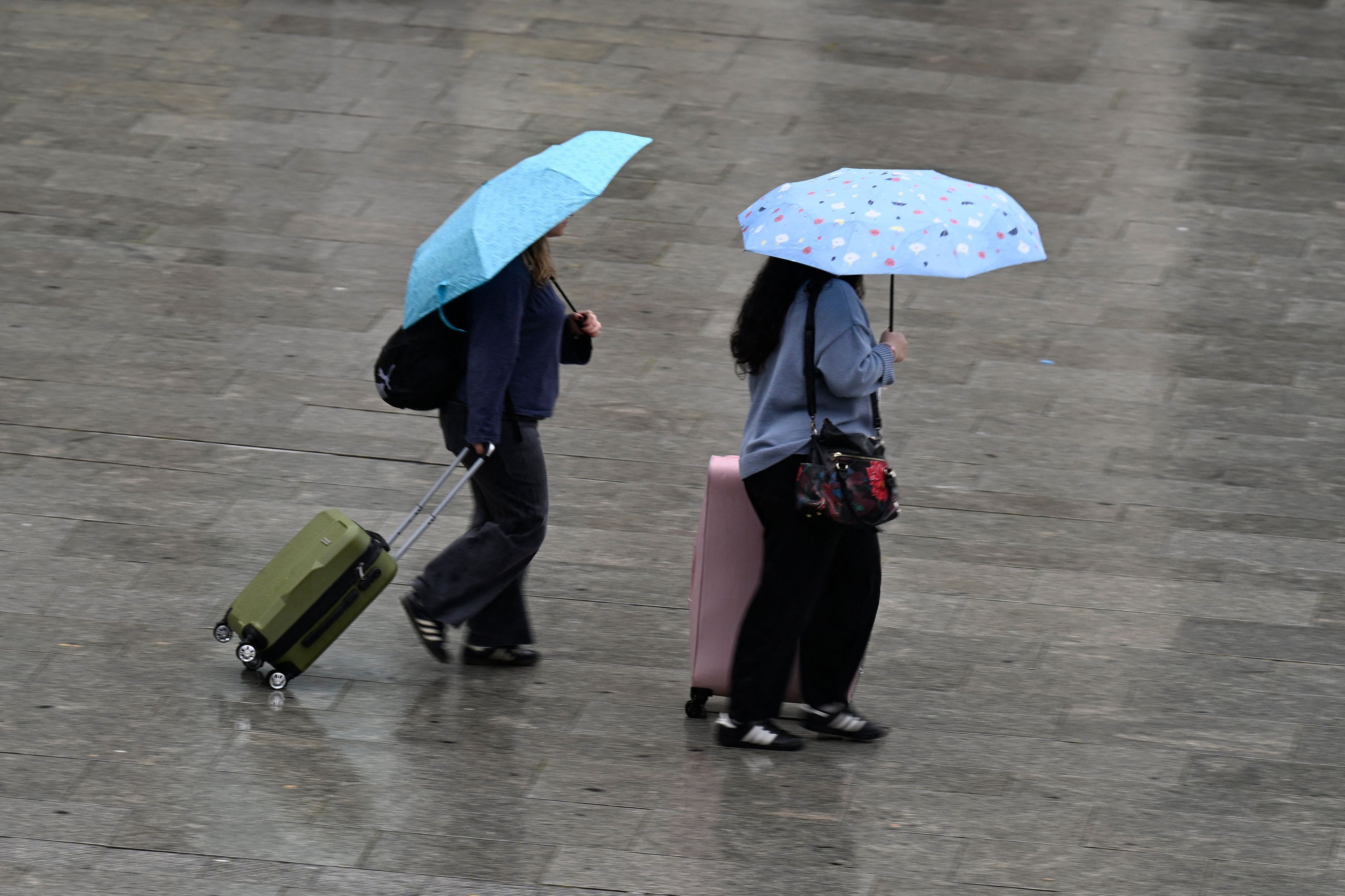 Köln: Passanten schützen sich auf dem Bahnhofsvorplatz mit Schirmen vor dem Regen (Archivbild)