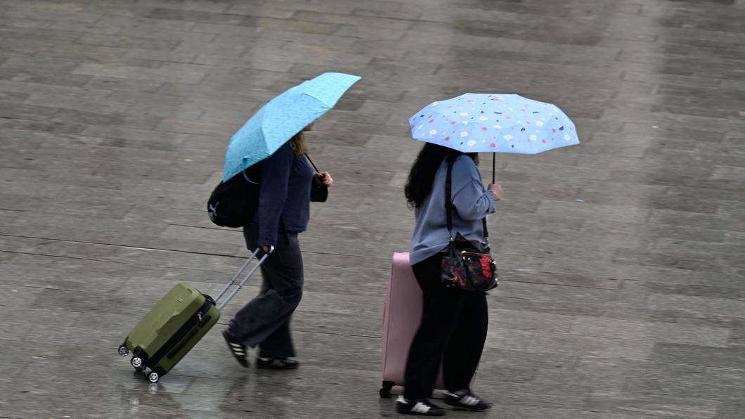 Köln: Passanten schützen sich auf dem Bahnhofsvorplatz mit Schirmen vor dem Regen (Archivbild)