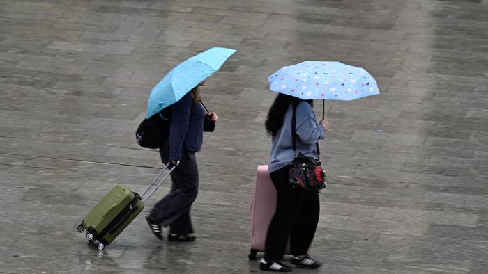 Köln: Passanten schützen sich auf dem Bahnhofsvorplatz mit Schirmen vor dem Regen (Archivbild)