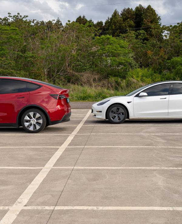 Tesla Model Y und Tesla Model 3 auf einem Parkplatz.