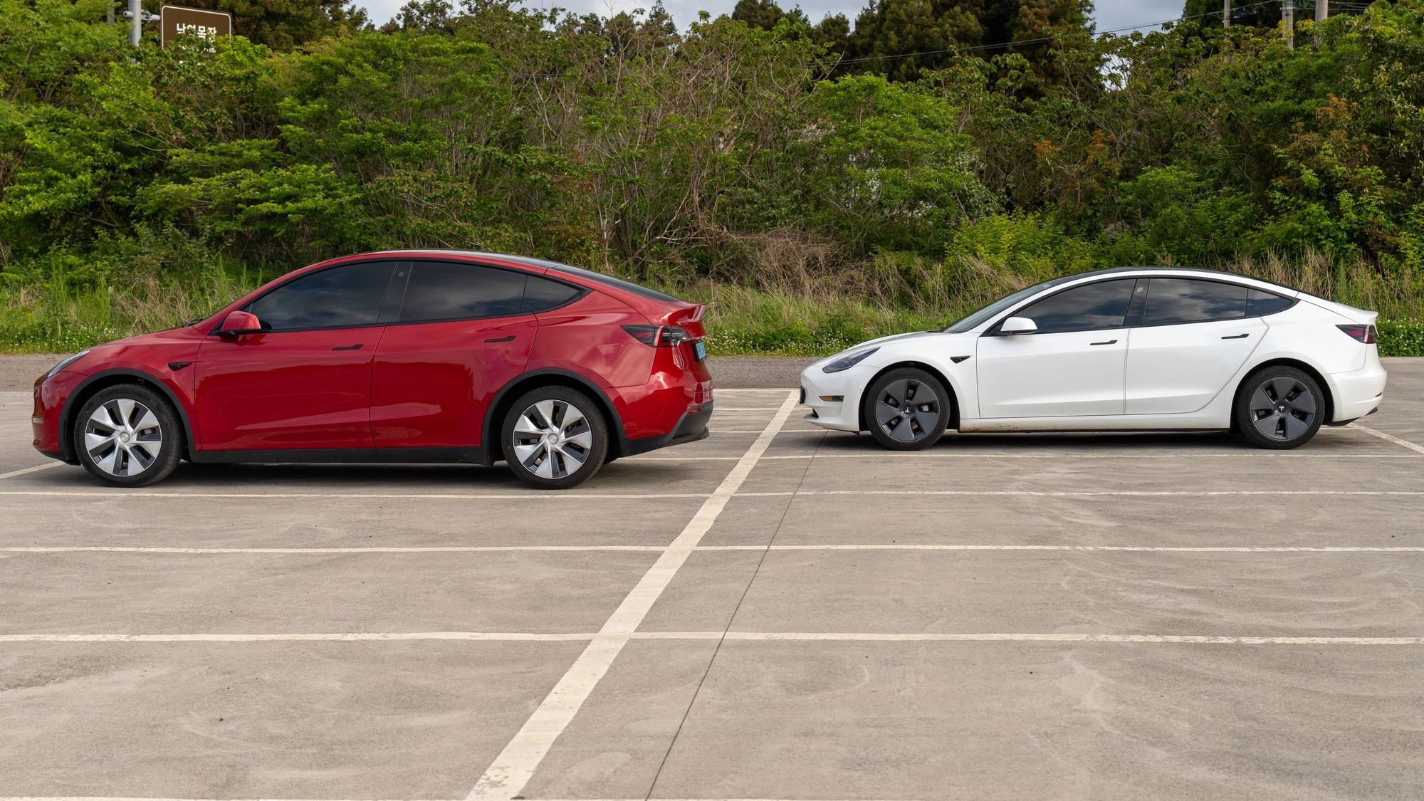 Tesla Model Y und Tesla Model 3 auf einem Parkplatz.