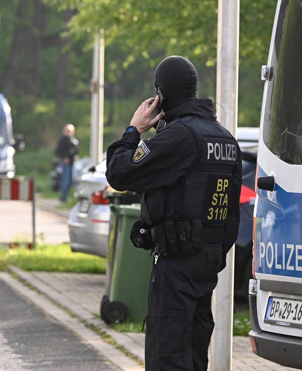 Ein Polizist telefoniert während einer laufenden Razzia