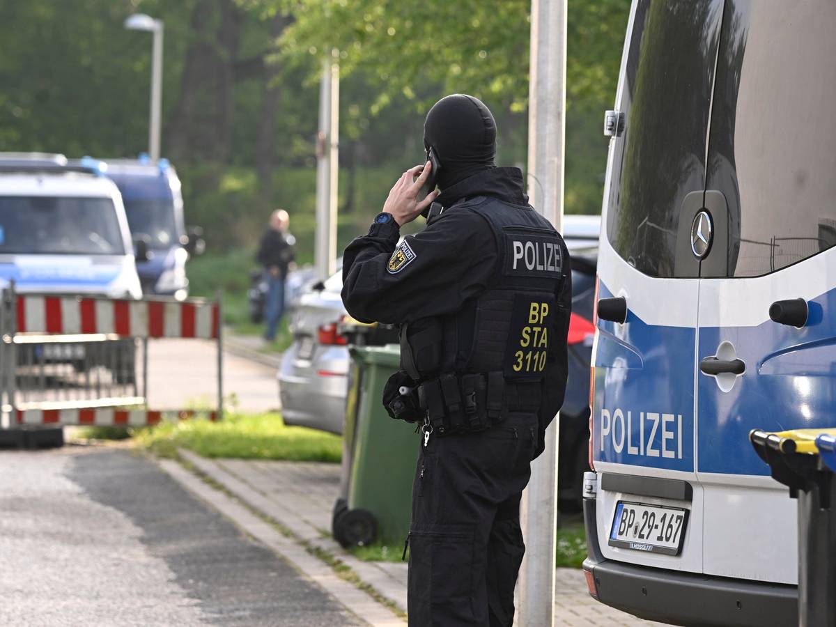 Ein Polizist telefoniert während einer laufenden Razzia