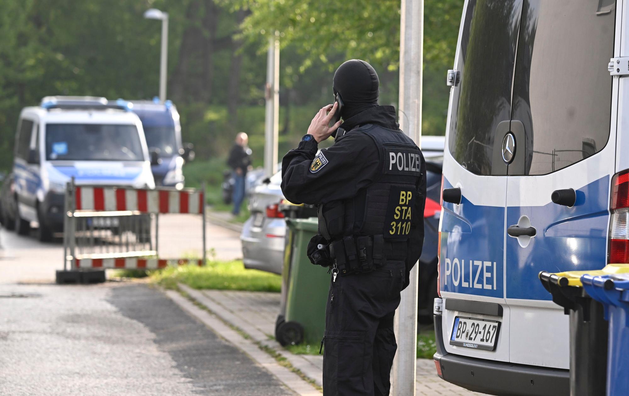 Ein Polizist telefoniert während einer laufenden Razzia