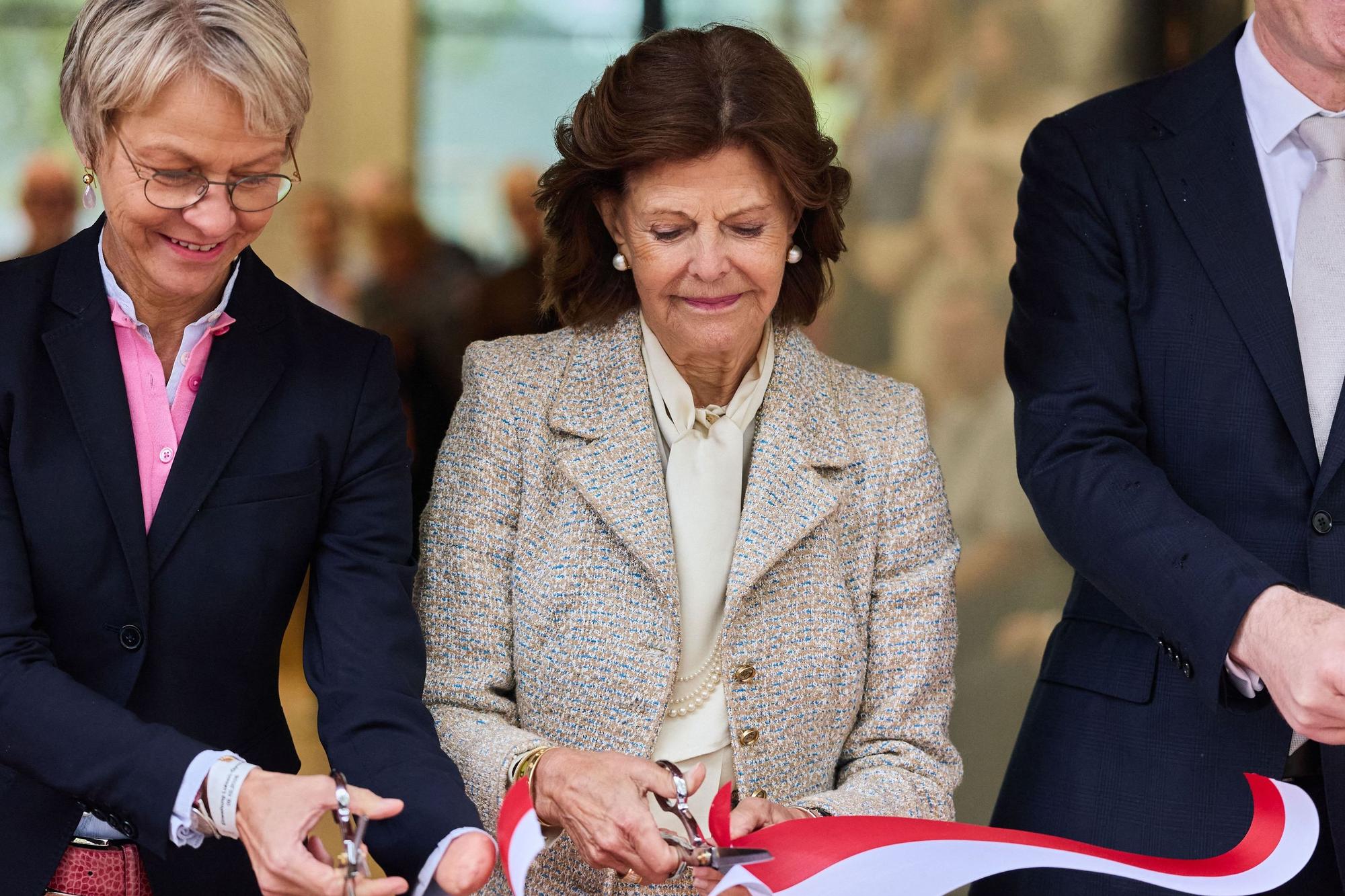 Königin Silvia von Schweden schneidet bei der Eröffnung des Luisen-Gymnasiums ein Band durch mit Dorothee Feller (l, CDU), Ministerin für Schule und Bildung des Landes Nordrhein-Westfalen, und Stephan Keller, Oberbürgermeister von Düsseldorf.