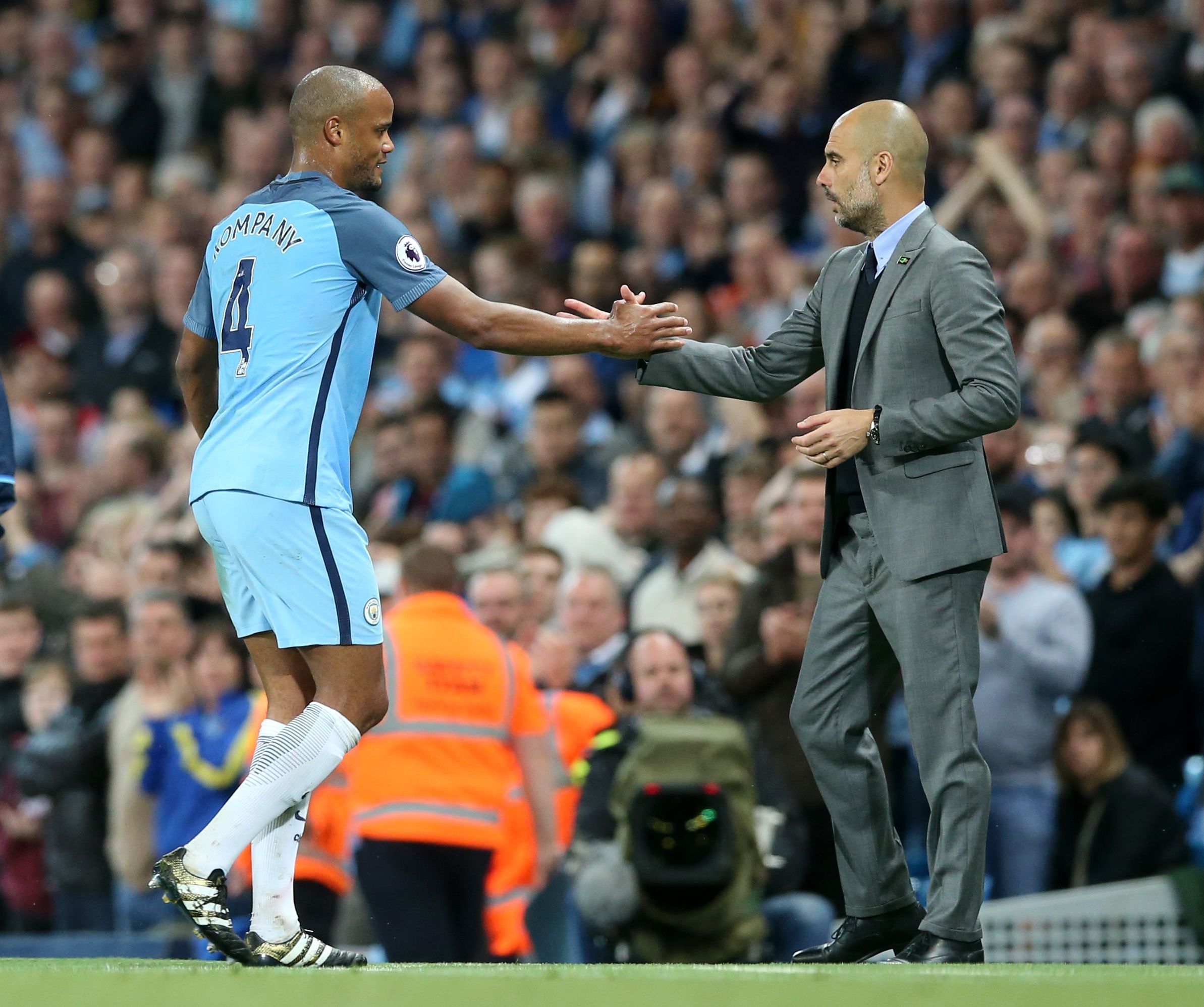 Manchesters Vincent Kompany und Trainer Pep Guardiola geben sich bei einer Auswechslung die Hand.