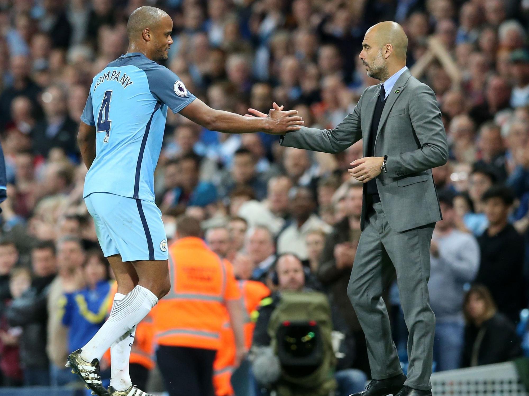 Manchesters Vincent Kompany und Trainer Pep Guardiola geben sich bei einer Auswechslung die Hand.