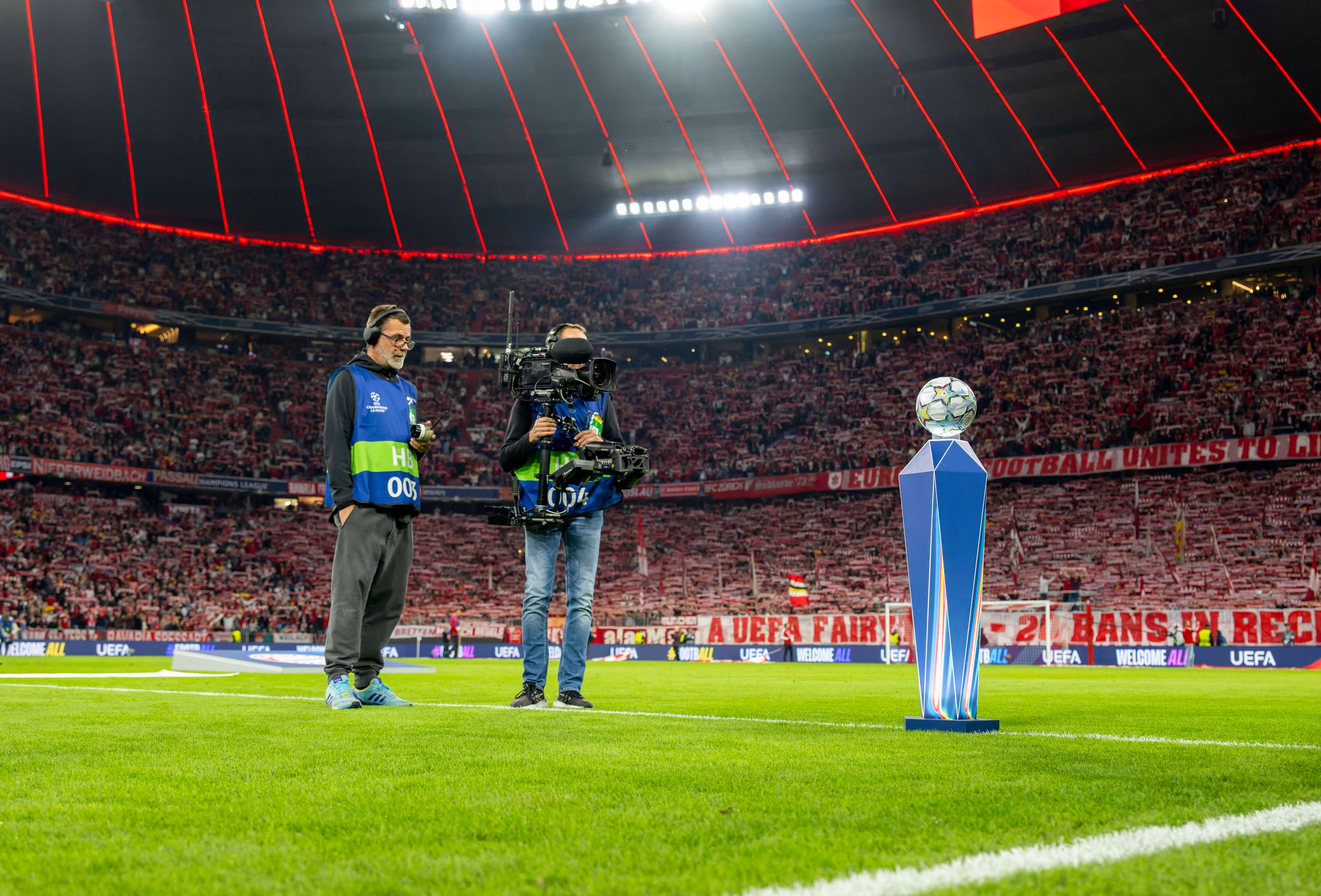 Ein Kamerateam filmt in der Champions League den Spielball auf dem Rasen.