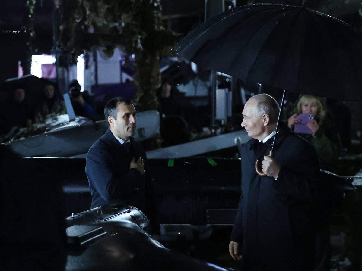 Der russische Präsident Wladimir Putin (rechts) hält einen Regenschirm in der Hand, während er am 2. Oktober 2026 bei einem Besuch eines Truppenübungsplatzes in der Region Tscheljabinsk im Regen steht.