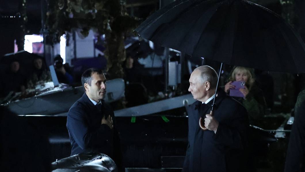 Der russische Präsident Wladimir Putin (rechts) hält einen Regenschirm in der Hand, während er am 2. Oktober 2026 bei einem Besuch eines Truppenübungsplatzes in der Region Tscheljabinsk im Regen steht.