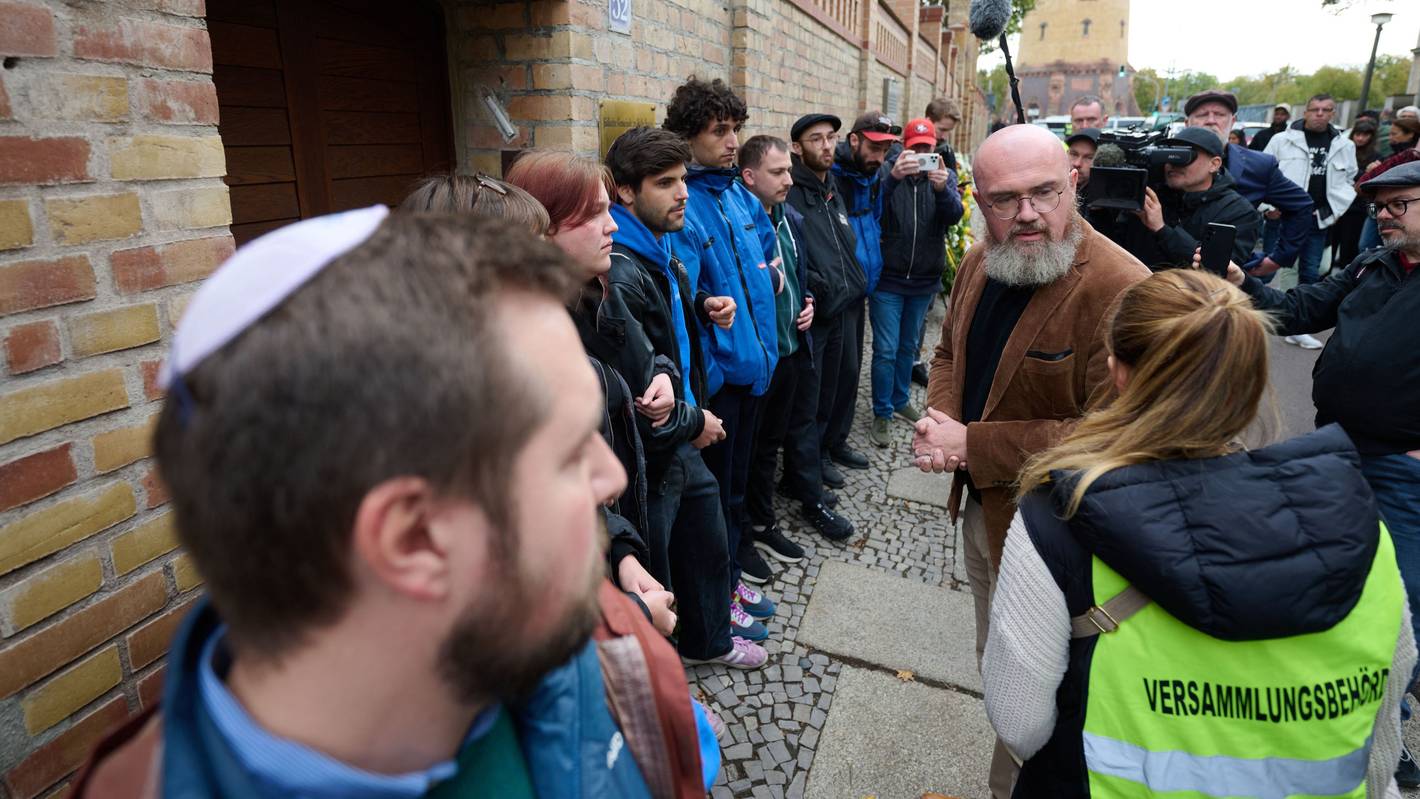 Hans-Thomas Tillschneider (AfD, r.) wird vor dem Eingang zur Synagoge in Halle/Saale von einer Mitarbeiterin der Versammlungsbehörde angesprochen. Tillschneider wollte am Gedenken für die Opfer des antisemitischen und rechtsextremen Terroranschlags von 2019 teilnehmen, wurde aber von Vertretern der Jüdischen Studierendenunion Deutschlands (l) nicht auf das Grundstück gelassen.