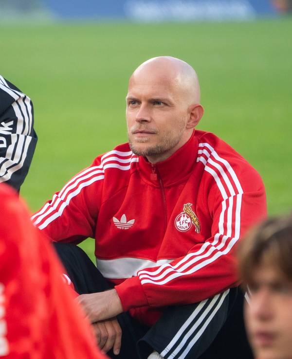 René Wagner sitzt mit seinem Team vor der Fankurve.
