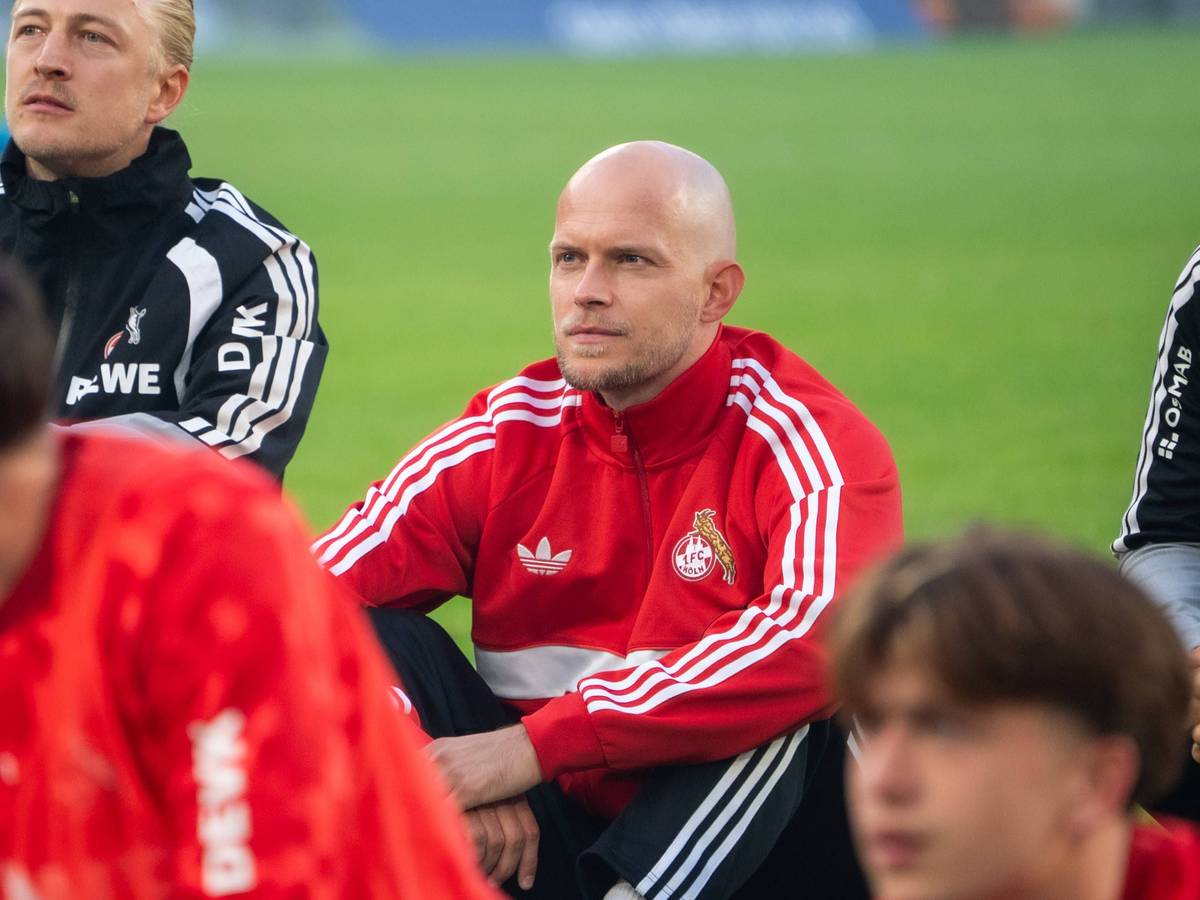 René Wagner sitzt mit seinem Team vor der Fankurve.