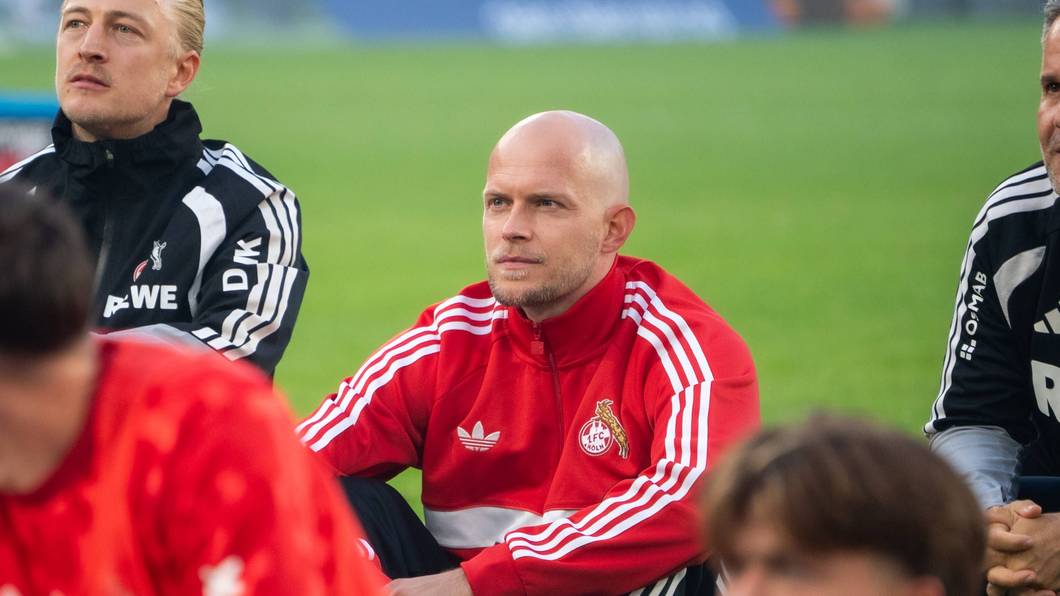 René Wagner sitzt mit seinem Team vor der Fankurve.