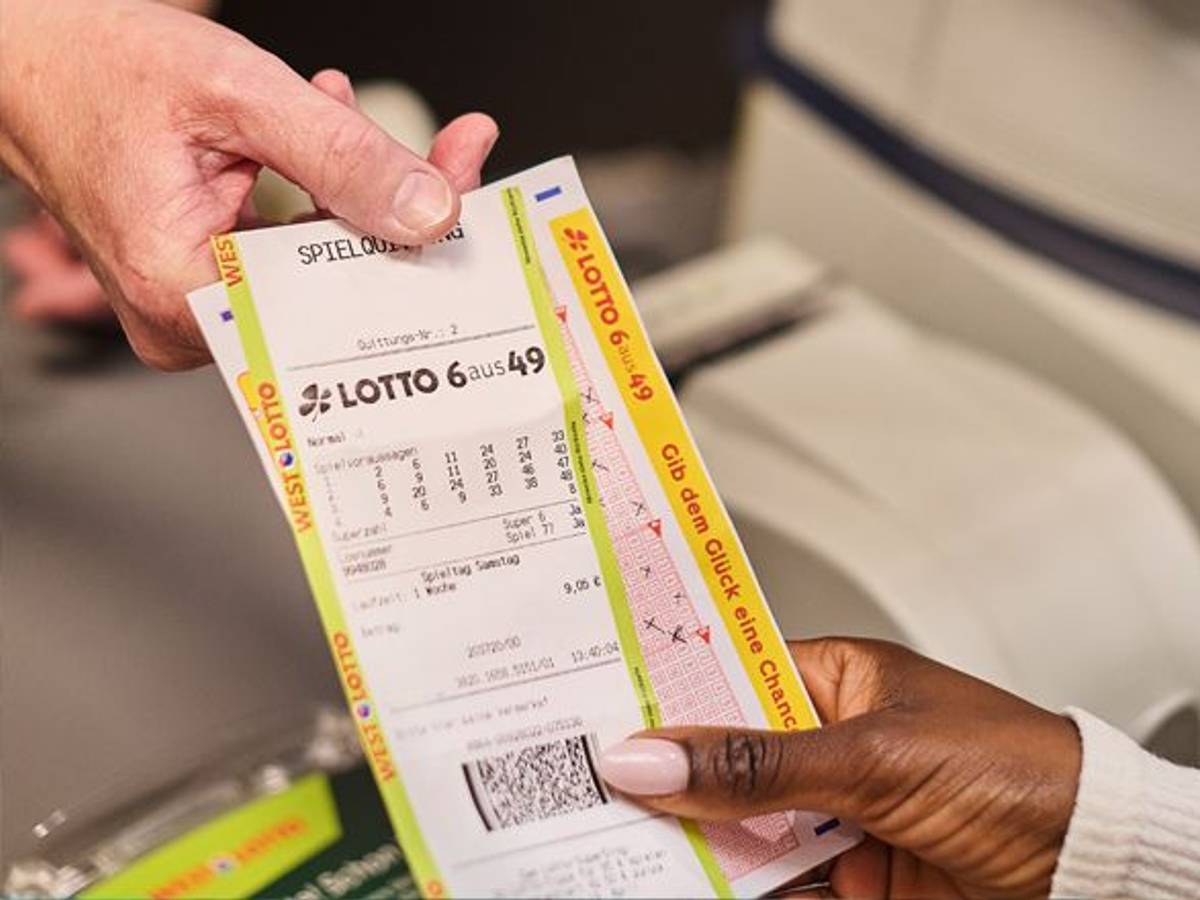Hand übergibt eine LOTTO-6aus49-Spielquittung an einer Annahmestelle.
