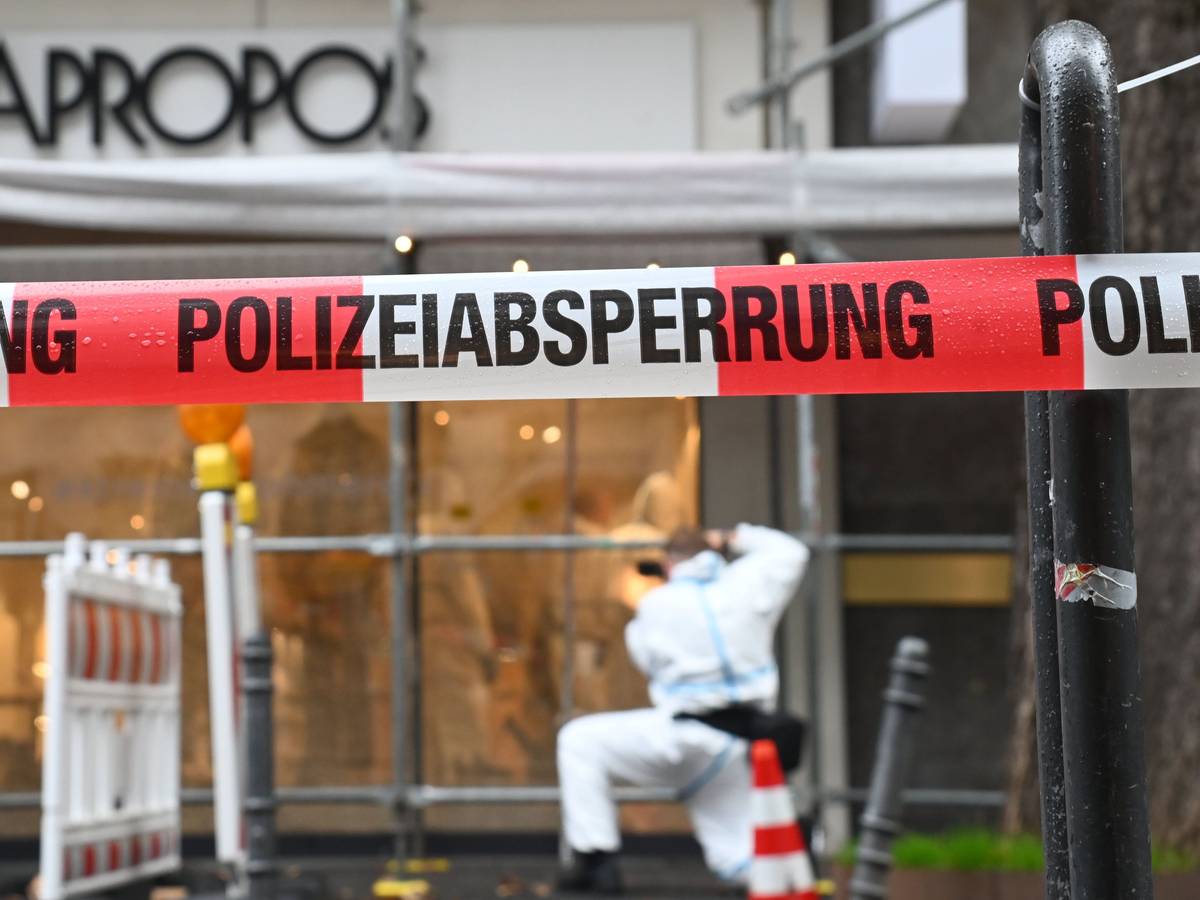 Ein Beamter im Schutzanzug sichert am Modegeschäft Spuren, der Tatort ist von der Polizei mit Flatterband abgesperrt worden.