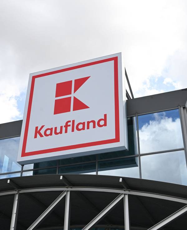 Ein Logo des Lebensmitteländlers Kaufland hängt an einem Haus.