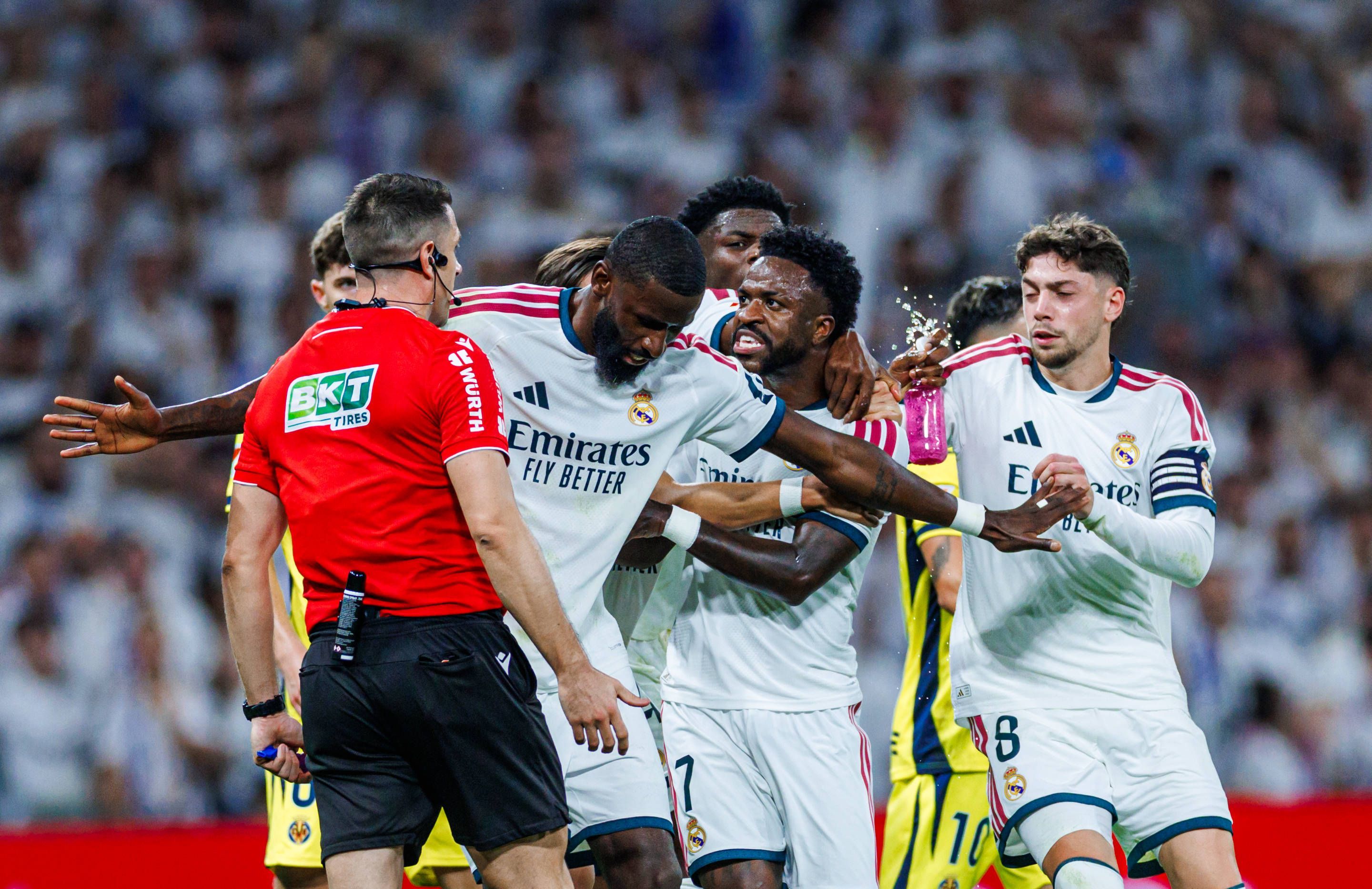 Antonio Rüdiger hält Vinicius Junior vom Schiedsrichter weg und stellt sich mit ausgebreiteten Armen dazwischen.