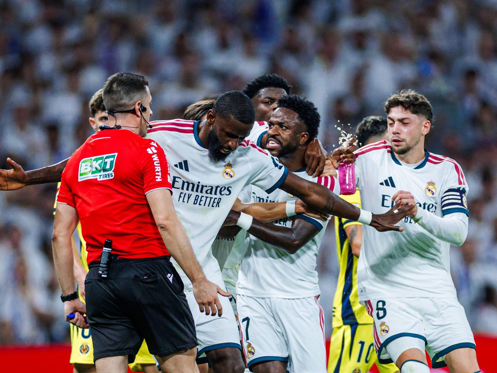 Antonio Rüdiger hält Vinicius Junior vom Schiedsrichter weg und stellt sich mit ausgebreiteten Armen dazwischen.