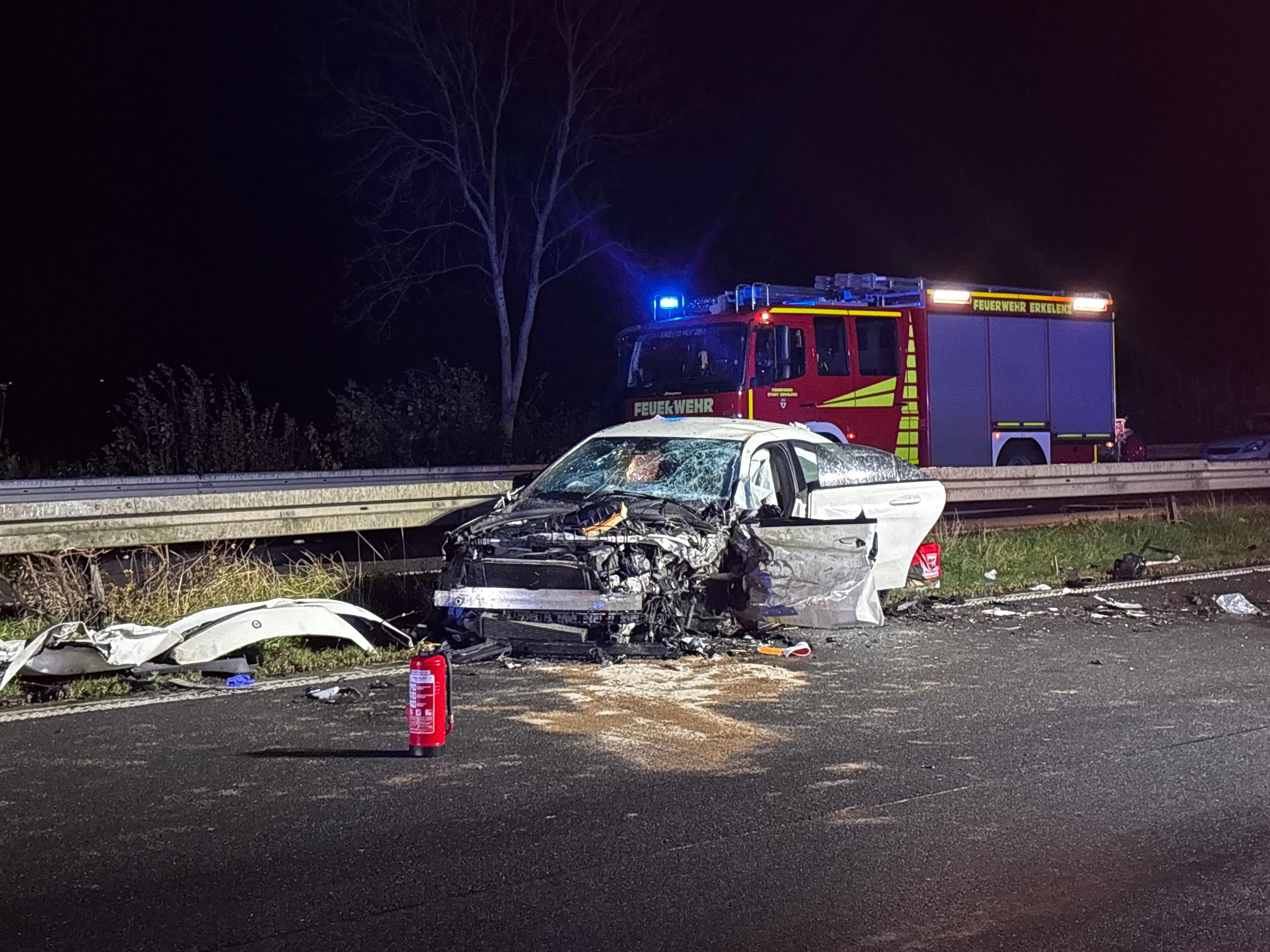 15.11.2025, Nordrhein-Westfalen, Heinsberg: Ein schwer beschädigtes Auto steht vor einem Einsatzfahrzeug der Feuerwehr auf der Autobahn. Bei einem schweren Unfall mit einem Geisterfahrer auf der A46 bei Heinsberg ist ein Autofahrer ums Leben gekommen. (zu dpa: «Tödlicher Unfall mit Geisterfahrer auf der A46» Foto: Justion Brosch/dpa +++ dpa-Bildfunk +++