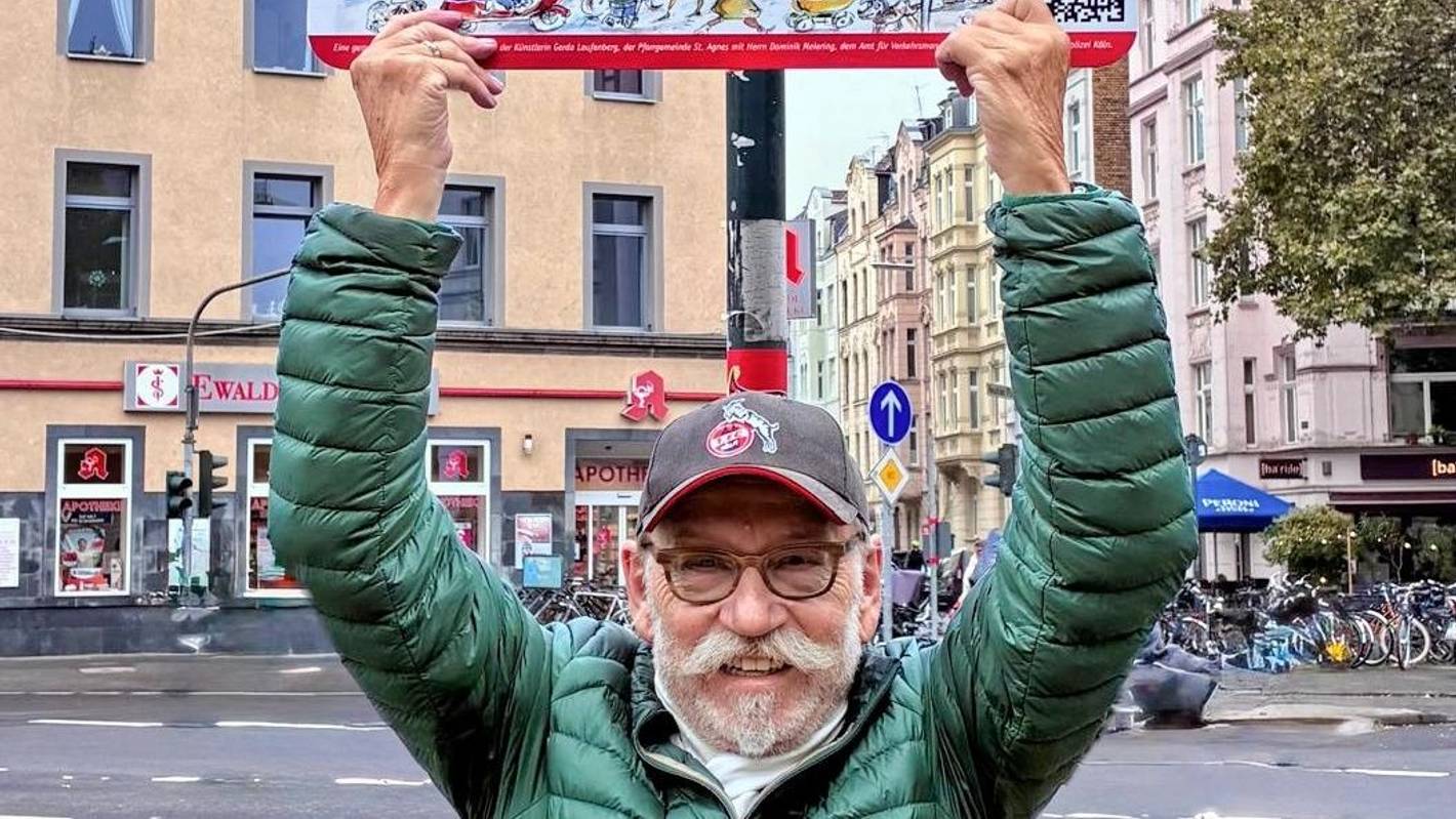 Janus Fröhlich zeigt ein Straßenschild.