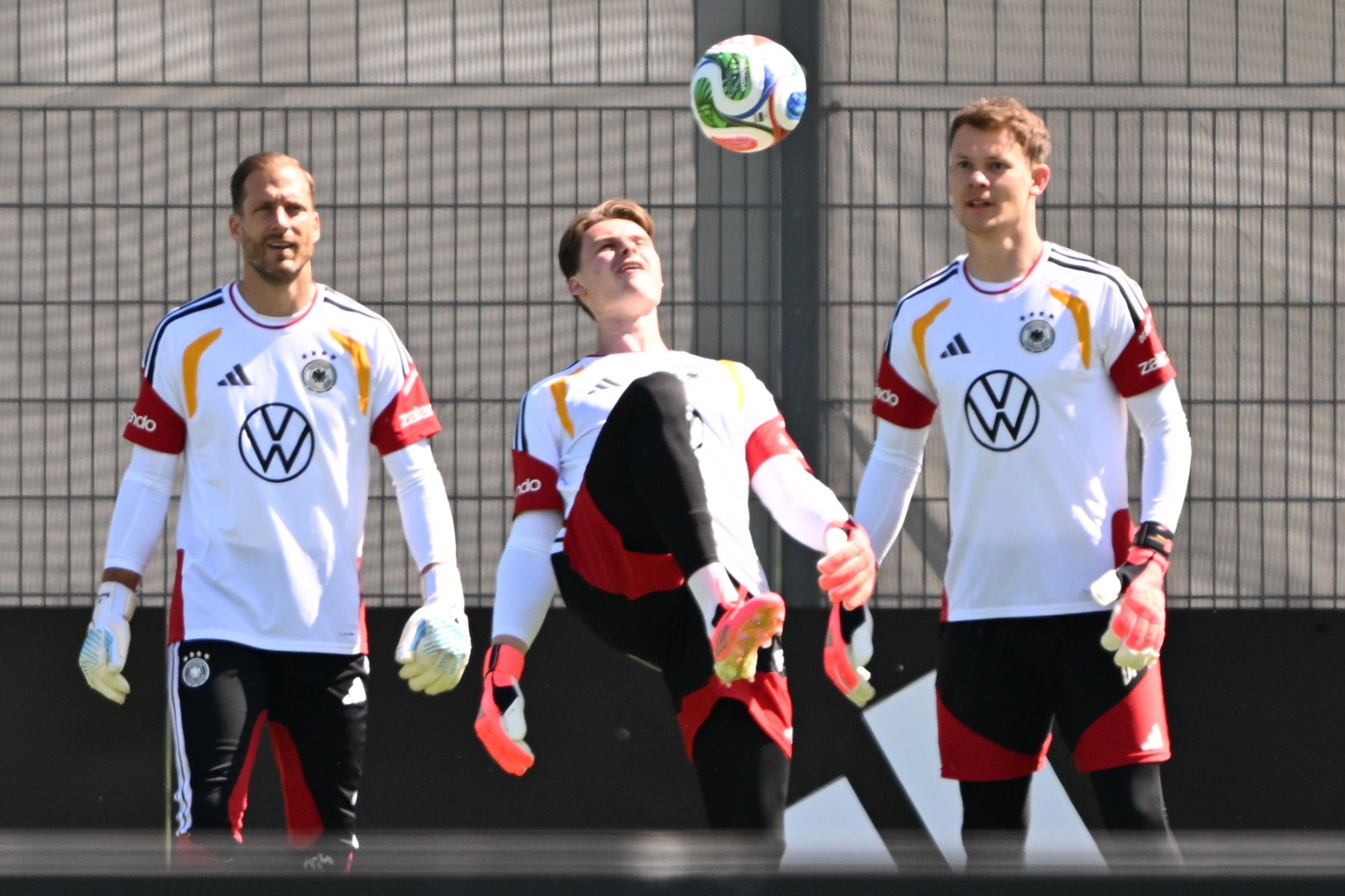 Jonas Urbig hält den Ball mit dem Oberschenkel hoch, Oliver Baumann und Alexander Nübel schauen ihm zu.