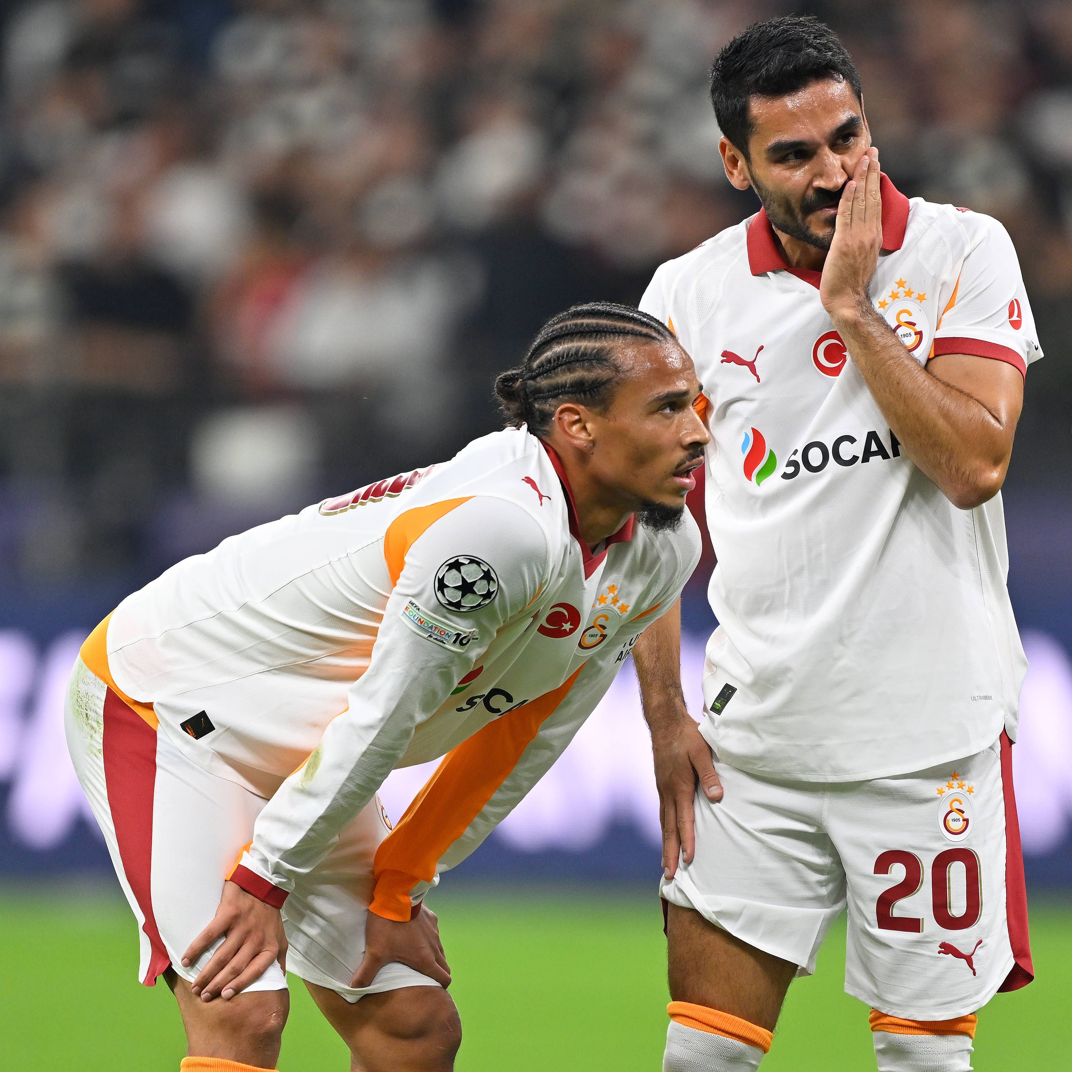 Leroy Sane und Ilkay Gündogan stehen auf dem Spielfeld und überlegen.