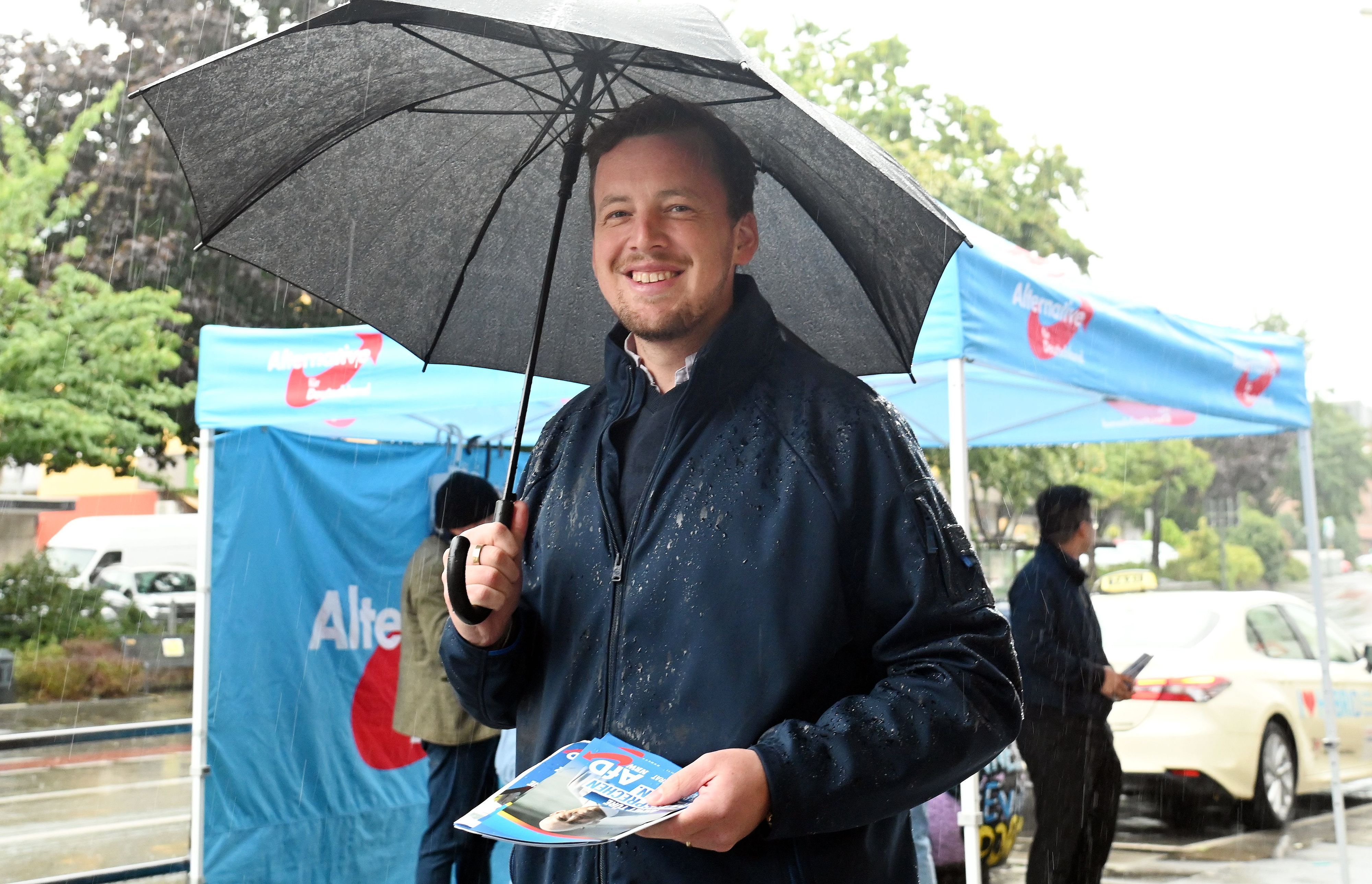 AfD-Politiker Matthias Büschges steht in Köln-Porz im Regen und macht Wahlkampf.