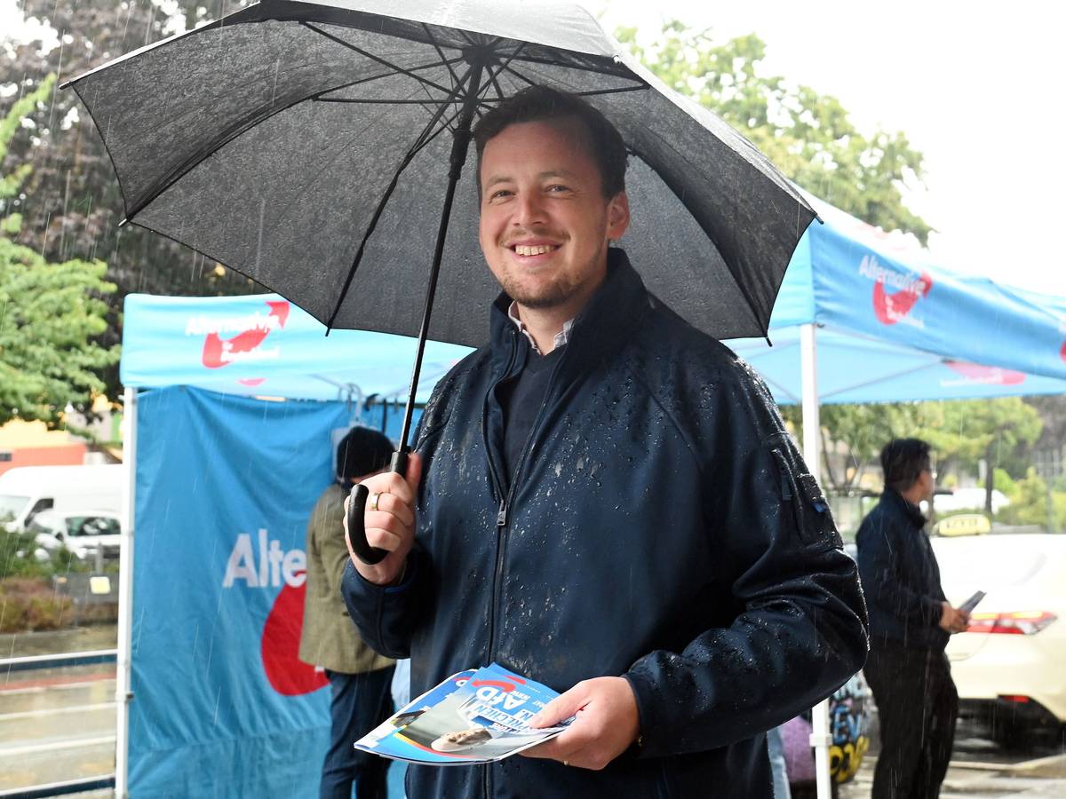AfD-Politiker Matthias Büschges steht in Köln-Porz im Regen und macht Wahlkampf.