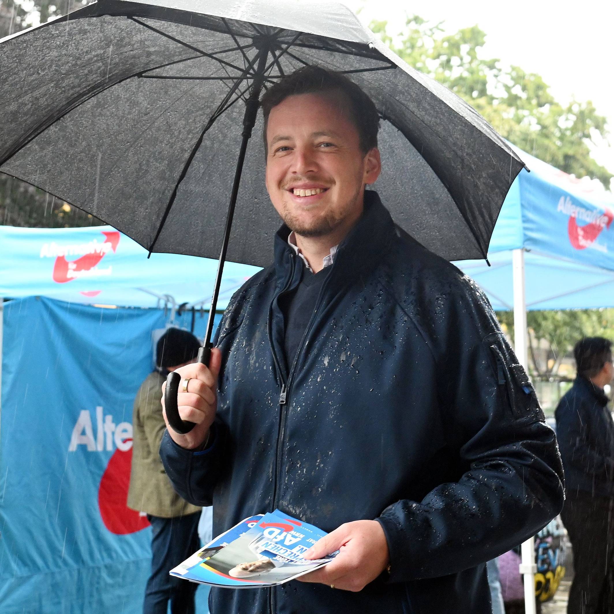 AfD-Politiker Matthias Büschges steht in Köln-Porz im Regen und macht Wahlkampf.