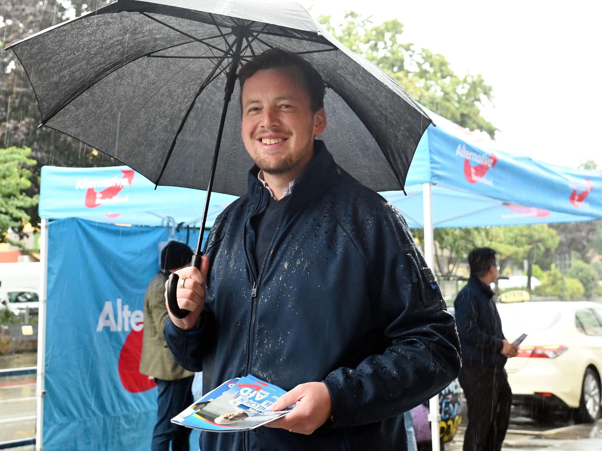 AfD-Politiker Matthias Büschges steht in Köln-Porz im Regen und macht Wahlkampf.