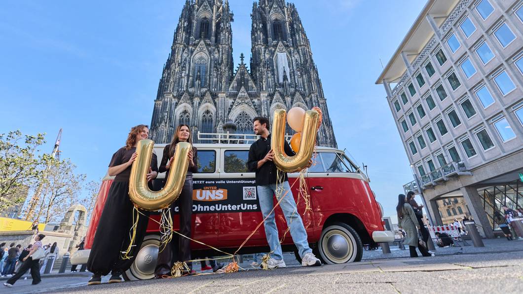 16.10.2026, Nordrhein-Westfalen, Köln: Milos Vukovic (r), Marie Zielcke (l) und Tabea Heynig, Schauspieler der RTL Daily Soap „Unter Uns“, stehen mit einem alten VW Bulli vor dem Dom. Die Schauspieler wollen für eine Fortführung der Serie werben, die RTL nach mehr als drei Jahrzehnten aus dem Programm nehmen wird. Foto: Rolf Vennenbernd/dpa +++ dpa-Bildfunk +++
