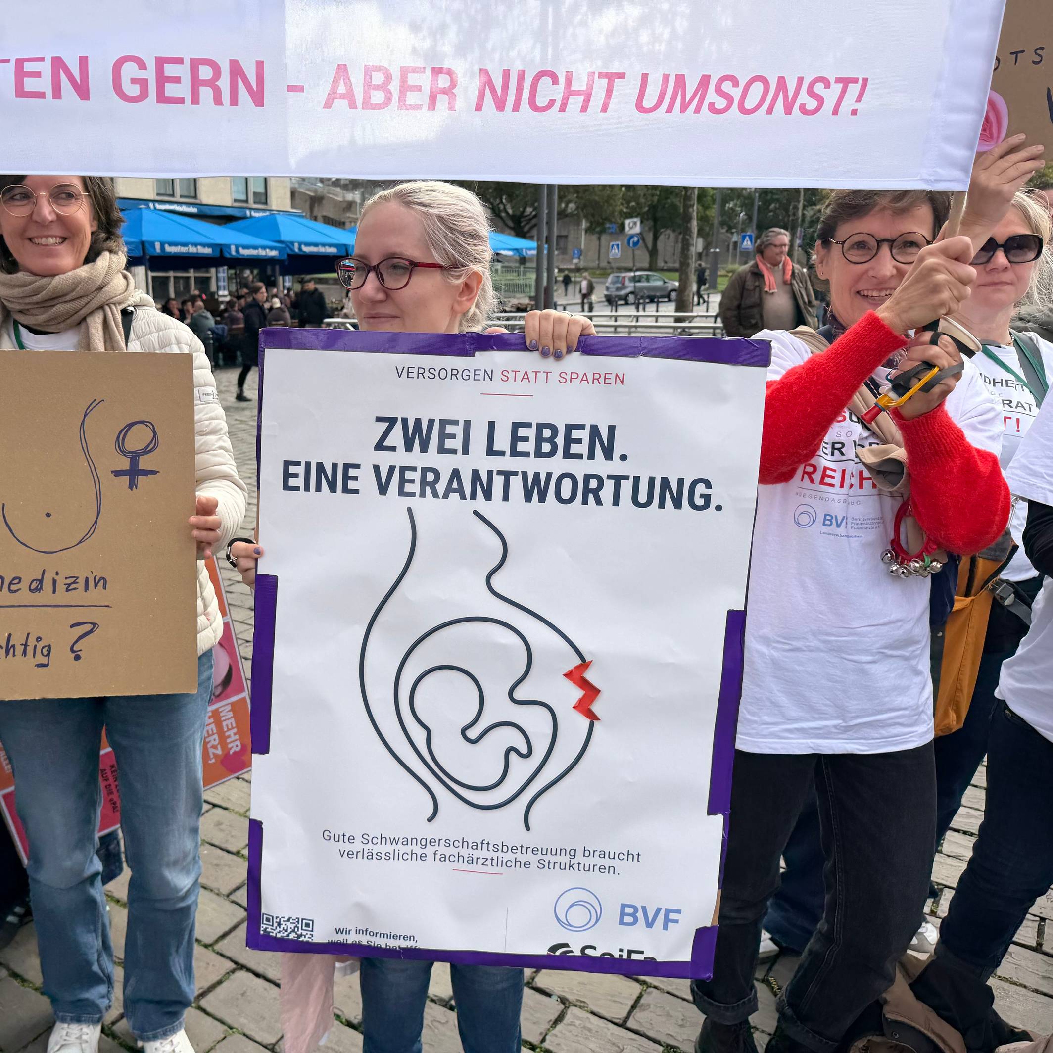 Frauen halten Transparente und selbstgemalte Plakate, darauf steht unter anderem die Frage „Frauenmedizin, nicht wichtig?“