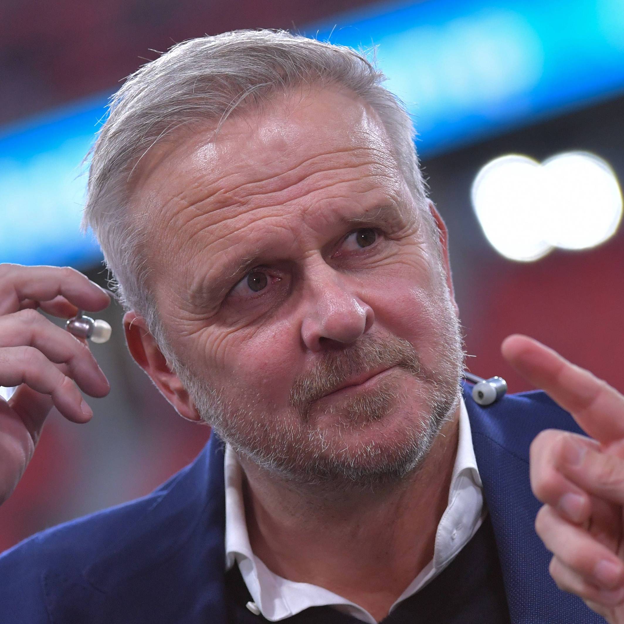 Dietmar Hamann steckt sich einen Kopfhörer ins Ohr.