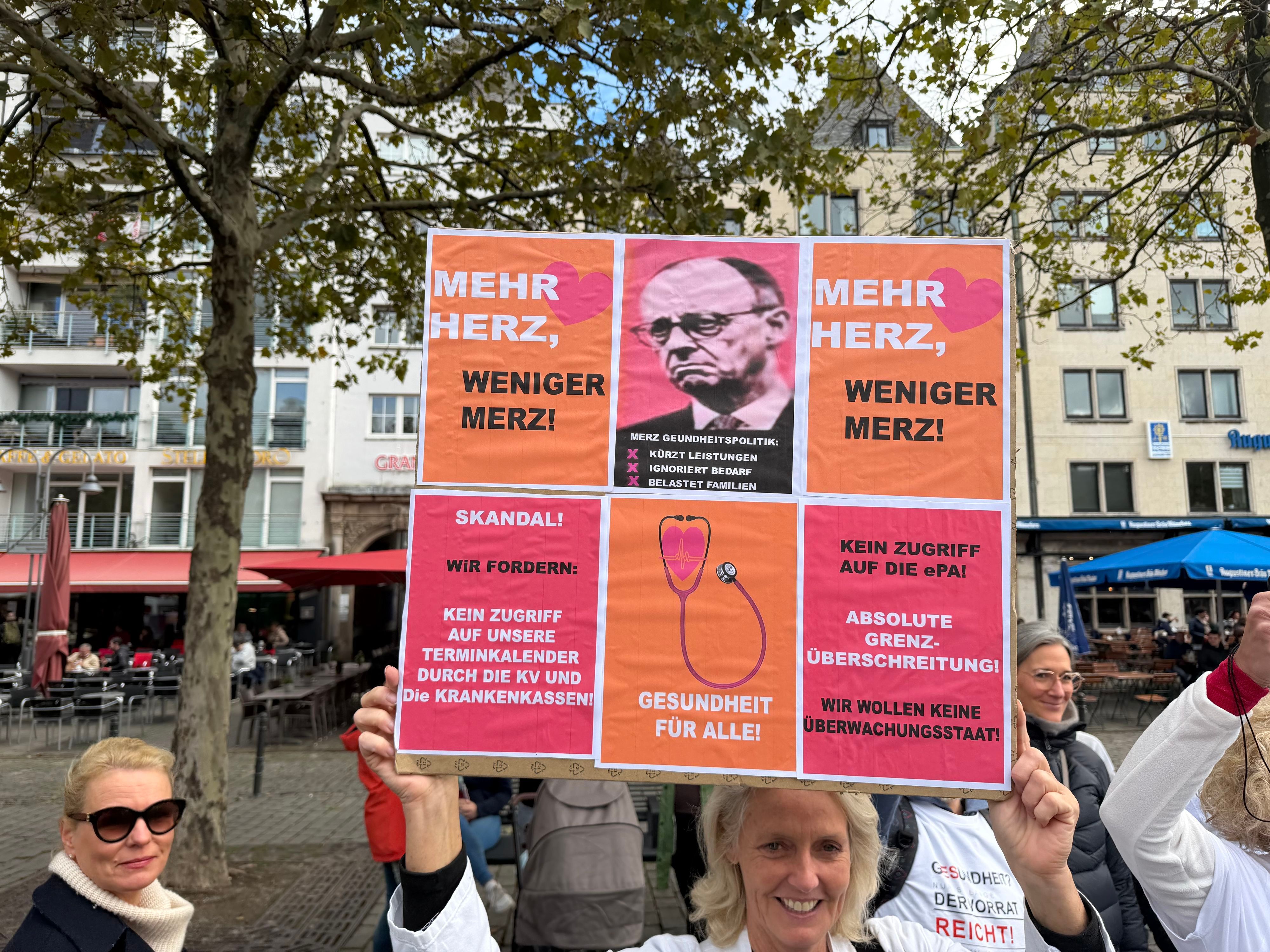 Eine Teilnehmende hält ein Plakat hoch mit der Forderung „Mehr Herz, weniger Merz“.